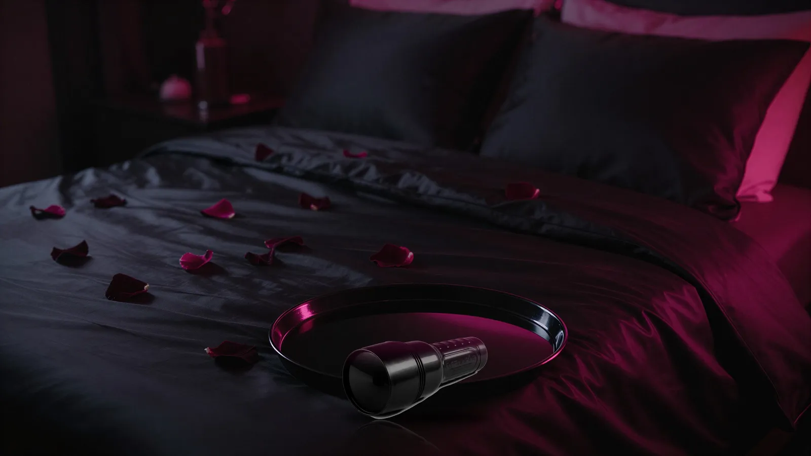 Closed black Fleshlight case on a glossy tray over dark satin sheets with rose petals and pink neon light