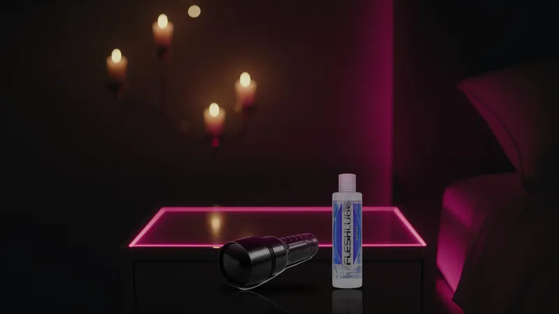 Closed black Fleshlight case and Fleshlube Water on a dark bedside table