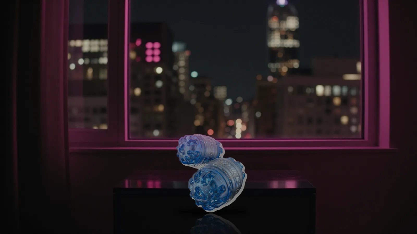 Quickshot Turbo on a nightstand in a city apartment at night with skyline bokeh and pink neon