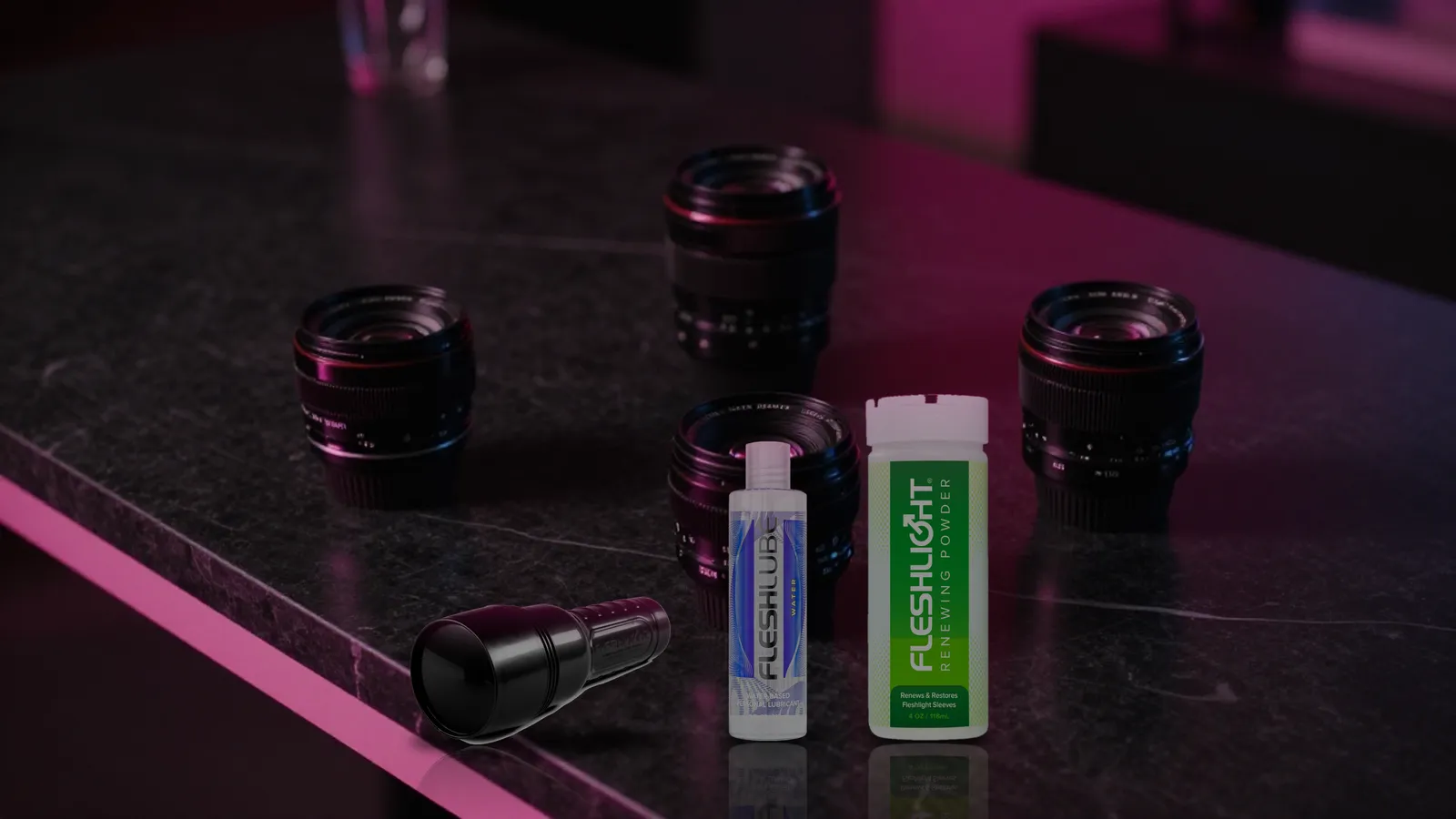 Closed Fleshlight case, Fleshlube Water, and Renewing Powder arranged on black marble